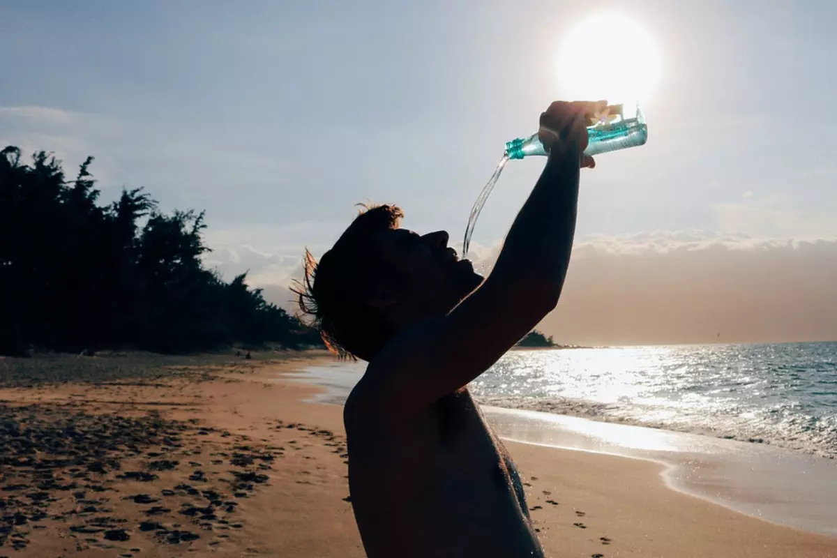 silhouette of a man drinking water on a beach