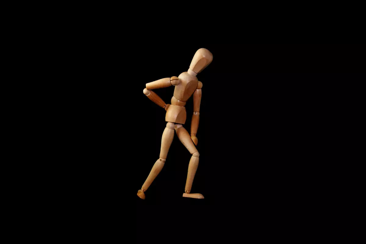 a wooden image of a man walking with back pain